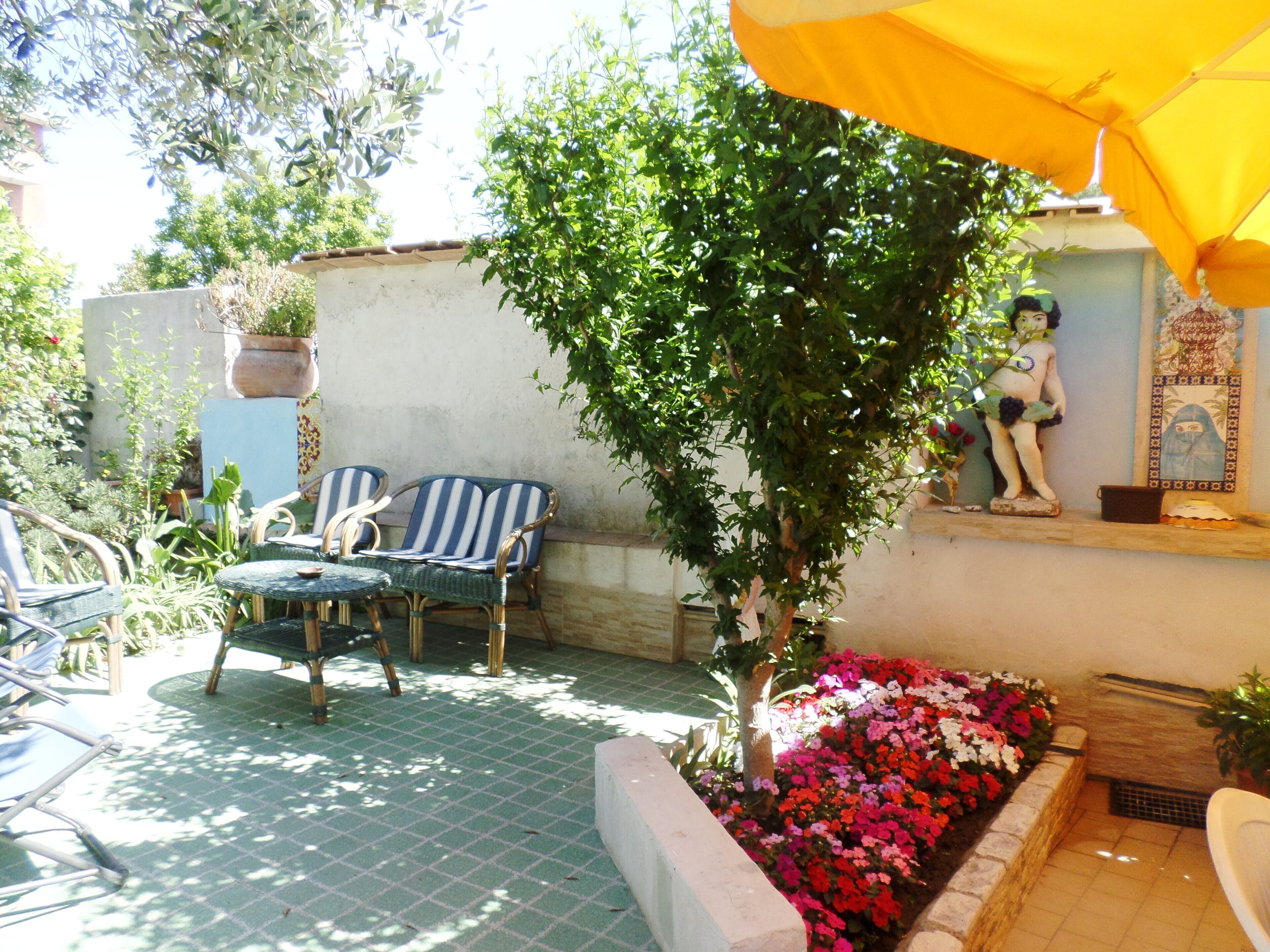 A patio area with outdoor furniture, a small tree, and a flower bed.