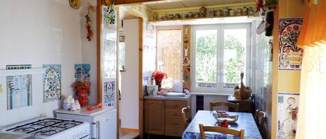 A kitchen with a gas stove, oven, and a dining area with a table and chairs.