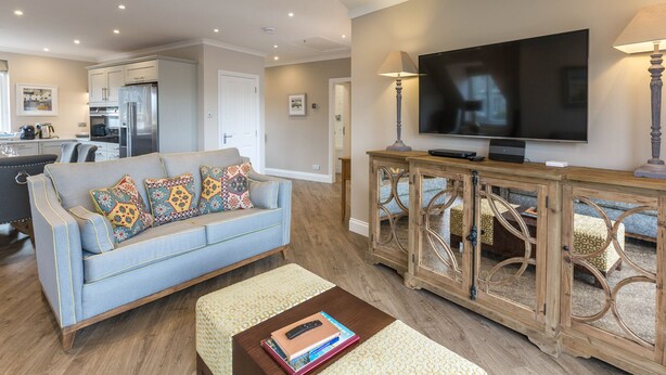 A modern living room with a sofa, coffee table, TV, and wooden console. - 1 Links Crescent 5 Star Selfcatering House Overlooking Old Course in St Andrews (St Andrews)