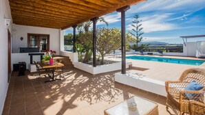 Eine überdachte Terrasse mit Pool, Gartenmöbeln und Blick auf die Landschaft.