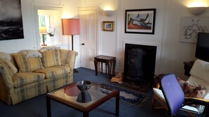 A living room with a sofa, a glass coffee table, a fireplace, and a television. - Fabulous House with Stunning Sea Views to Skye. By NTS gardens. Great Privacy. (Kyle of Lochalsh)