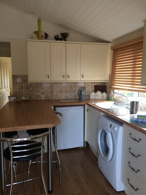 Compact kitchen with washing machine, white cabinets, and a tiled backsplash.