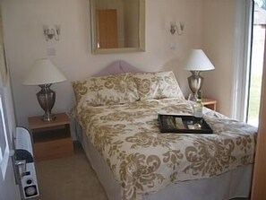 Restful retreat with a neatly made bed, bedside lamps, and a wall-mounted mirror.