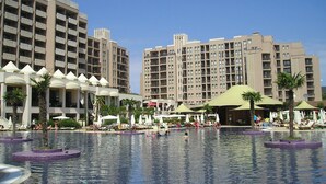 Ein Hotel mit mehreren Etagen, einem Außenpool und Liegestühlen.