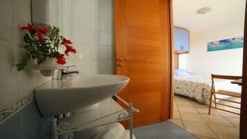 Ein Badezimmer mit Waschbecken, Spiegel und einer Tür zu einem Schlafzimmer mit Bett und Sessel.