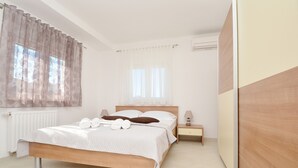 A bedroom with a wooden bed, white bedding, a nightstand with a lamp, and a window with sheer curtains. - Apartment Palm Beach 2 for 6-8 persons - Amazing beach house rental! (Okrug Gornji)
