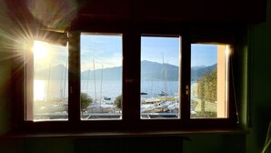 Uma janela com vista para uma marina e montanhas.