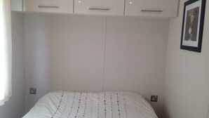 A bedroom with a bed, white walls, and a framed picture on the wall. - MARSHLANDS LAKESIDE NATURE RETREAT (Barton-upon-Humber)