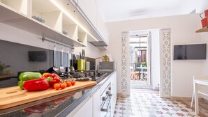 A modern kitchen with a wooden countertop, a TV mounted on the wall, and a patterned tile floor.