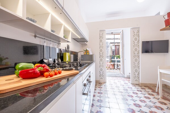 Een moderne keuken met een houten aanrecht, een aan de muur bevestigde televisie en een vloer met een patroon van tegels.