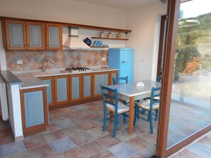 Une cuisine avec des meubles de rangement en bois, une cuisinière à gaz, un évier et un réfrigérateur bleu.