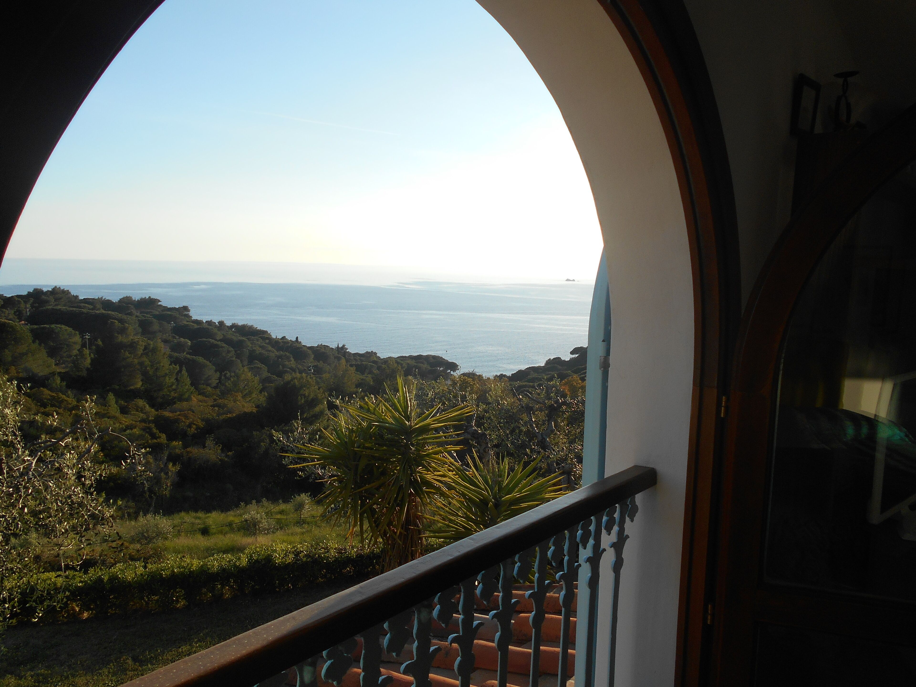 A balcony with a view of the sea and hills.
