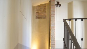 A staircase with a brick wall and a light fixture above it.