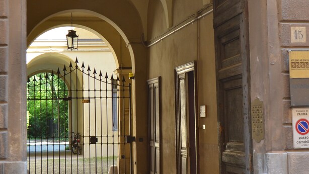 An arched entrance with a metal gate, a door, and a sign with the number 15.