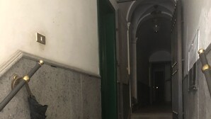 A staircase with a green door at the top, a wall-mounted light fixture, and a tiled floor. - Apartment 3 minutes from the Spanish Steps (2 rooms) with a / c  (Roma)