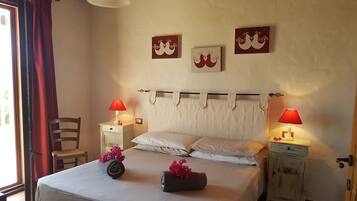 Un dormitorio con una cama, dos mesitas de noche con lámparas, una silla y una ventana con cortinas.