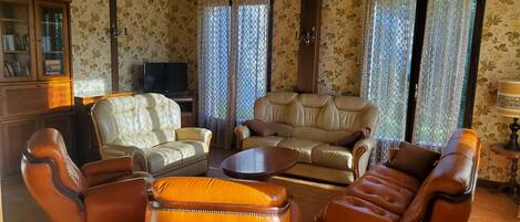 A living room with leather sofas, a wooden coffee table, and a television on a cabinet.