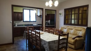 Un coin repas avec une table dressée pour quatre personnes, entourée de chaises en bois. Un canapé en cuir est placé contre le mur.