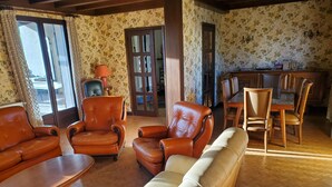 Un salon avec des canapés en cuir, une table basse en bois et un coin repas comprenant des chaises et une table en bois.