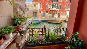 Un balcón con plantas en macetas y vistas a un canal con barcos.