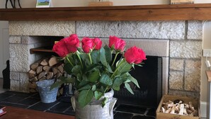 Un salón con chimenea, un cuadro de un toro y un jarrón con rosas rojas.