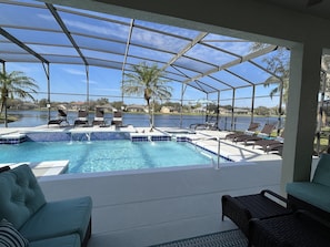 A covered outdoor swimming pool with lounge chairs and a view of a lake. - Lakeview Retreat: luxury 5★ villa -large pool, spa, game room, near parks & golf (Kissimmee)