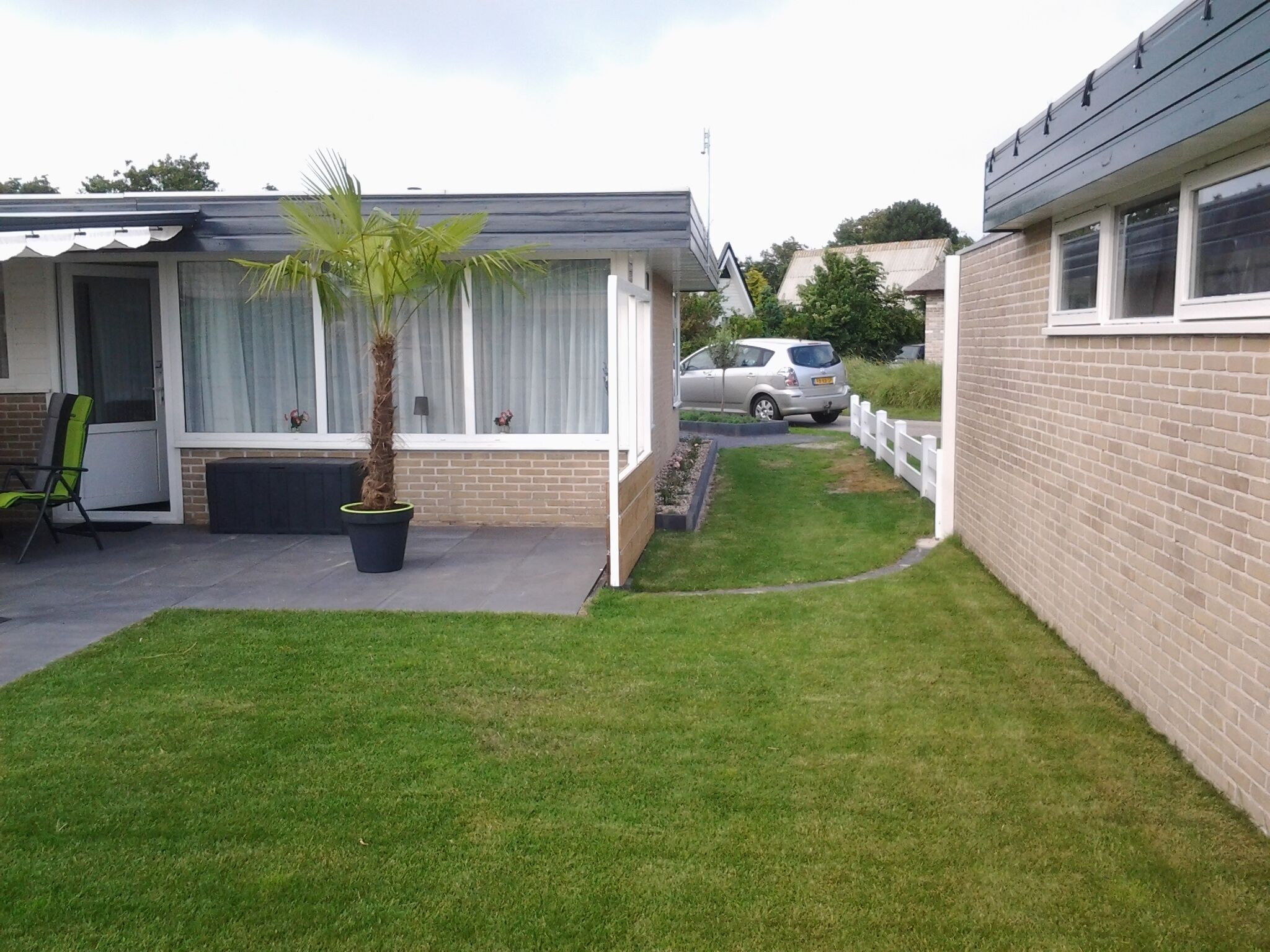 A residential property with a well-maintained lawn, a single-story brick house, and a car parked in the driveway.