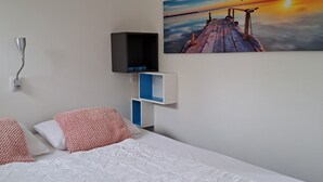 Habitación de hotel con cama, un cuadro de un atardecer, televisor y mesita de noche.