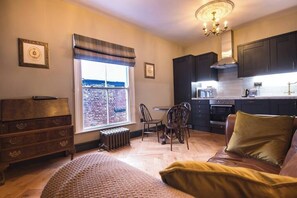 A cozy room with a bed, a window with a view, a dining area, and a kitchen.