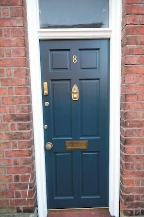 A dark blue door with the number 8, a brass knocker, and a brass mail slot.