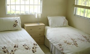 Camera da letto con due letti, un comodino e una finestra con sbarre.