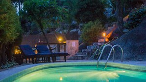 A swimming pool with lounge chairs and a small table, surrounded by trees and a stone wall. - Sun, Sea & Culture. Luxury Villa & Pool. Breathtaking Views to Sea. Inc WiFi (Santa Cristina d'Aro)