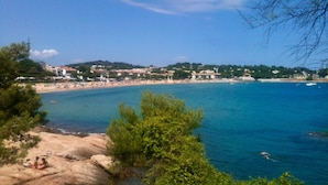 A coastal town with a beach, rocky shoreline, and buildings in the background. - Sun, Sea & Culture. Luxury Villa & Pool. Breathtaking Views to Sea. Inc WiFi (Santa Cristina d'Aro)