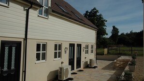 A two-story building with a beige exterior, multiple windows, and a tiled patio area. - Holiday Cottage 1 mile from Bruton (Bruton)