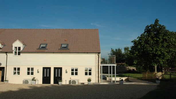 A two-story building with a tiled roof, a front entrance, and a small balcony. - Holiday Cottage 1 mile from Bruton (Bruton)