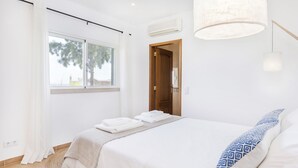 A hotel room with a bed, a window with curtains, a door, and a hanging light fixture. - Sea View !!! 2 bedrooms (Almancil)