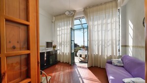 A room with a purple sofa, a wooden cabinet, and a view through a glass door to an outdoor area. - B&B NARCISO with private parking (Conca dei Marini, Campania)