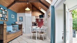 Una habitación acogedora con techo de madera, una mesa de comedor con sillas, un sofá con cojines y un televisor en la pared.