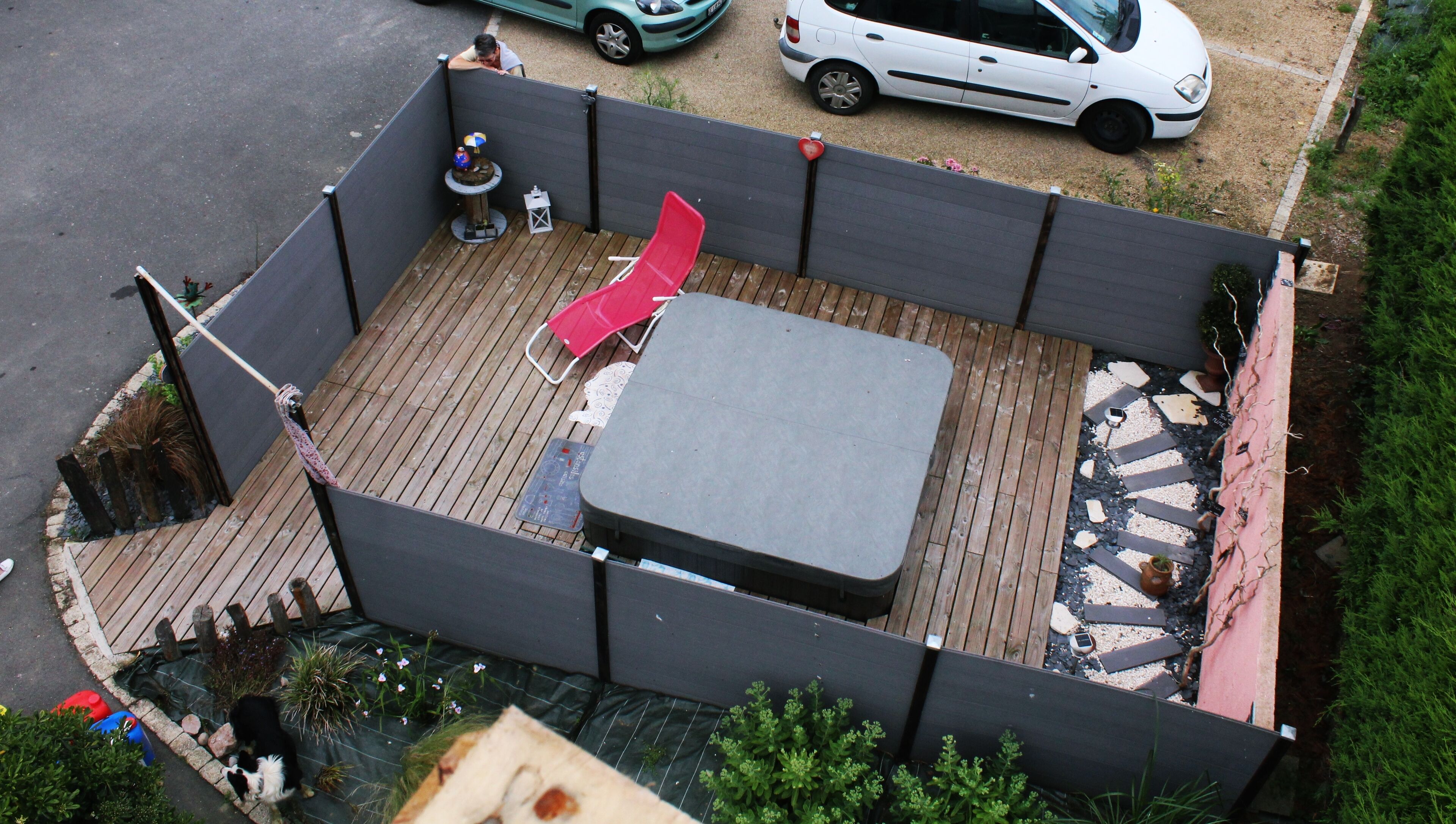 A rooftop deck with a wooden floor, a rectangular table, and a red chair.