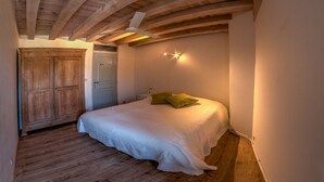 A bedroom with a bed, wooden wardrobe, and a ceiling fan. - Renovated stone house with swimming pool - 150 m from the medieval castle of Larressingle (Larressingle)