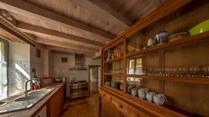 A kitchen with wooden beams, a sink, a stove, and a cabinet with glassware. - Renovated stone house with swimming pool - 150 m from the medieval castle of Larressingle (Larressingle)