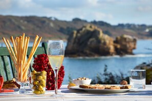 A table with a glass of white wine, a glass of water, a plate of bread, a bowl of nuts, and a glass of olive oil. - Exceptional site, feet in the water, on a wild island - all seasons (Trébeurden)