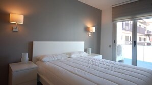 Une chambre d’hôtel moderne avec un grand lit, deux tables de chevet et une vue sur le balcon extérieur.