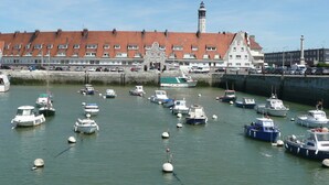 A harbor with numerous boats docked, a prominent lighthouse, and a row of brick buildings with a red-tiled roof. - Studio 3*, SEA VIEW and facing the dragon, 150m from the BEACH, near the 2 caps site (Calais)