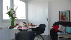 Un coin repas avec une table mise pour le petit-déjeuner, un vase rempli de fleurs et un tableau accroché au mur.