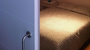 Una habitación con una cama, una mesita de noche, una lámpara y un aplique en el techo.