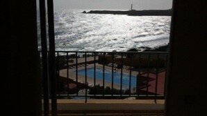 Un balcón con vista al océano y un faro distante.