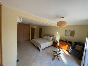 A bedroom with a bed, bedside tables, a small round table, a sofa, and a mirror on the wall.