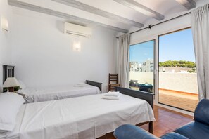 Quarto de hotel com duas camas, uma janela com vista para edifícios e uma varanda.