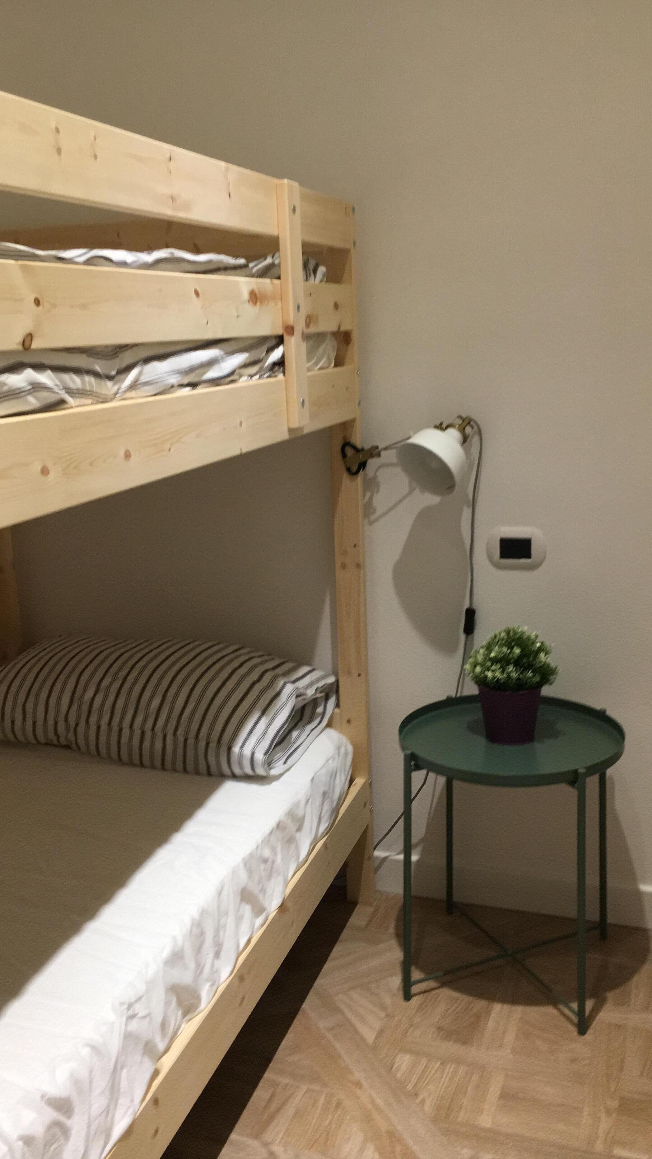 Uma cama beliche com mesa de cabeceira e abajur.